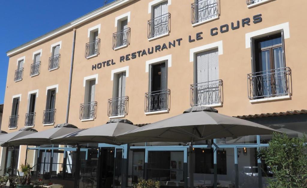 un edificio con ombrelloni di fronte di Logis Le Cours a Saint-Gilles