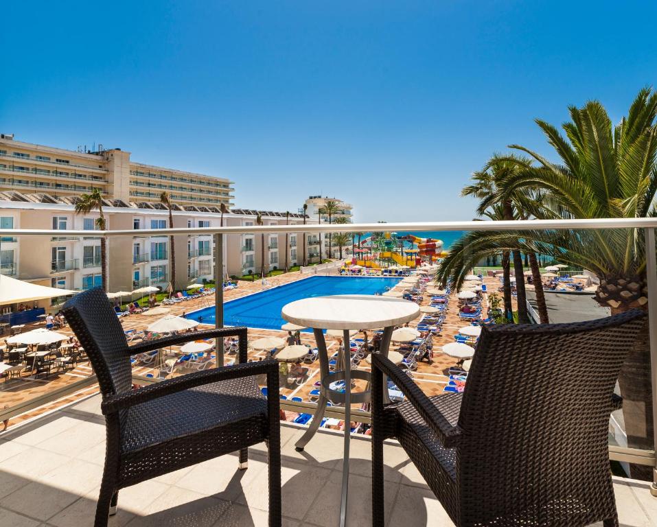 balcón con mesa, sillas y piscina en Globales Playa Estepona, en Estepona