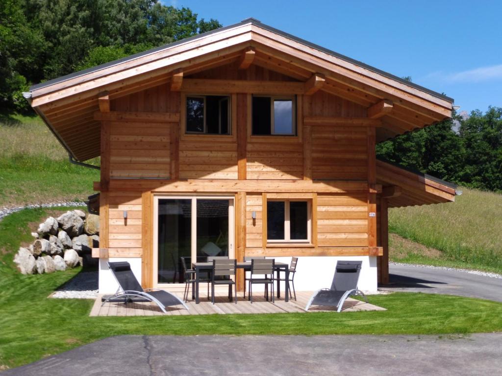 a log cabin with a table and chairs on a deck at Les Ours de Combloux in Combloux