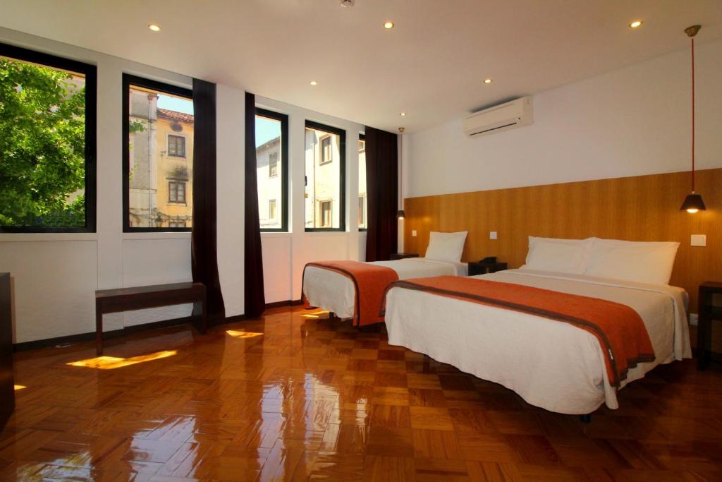 a hotel room with two beds and two windows at Moderna in Coimbra