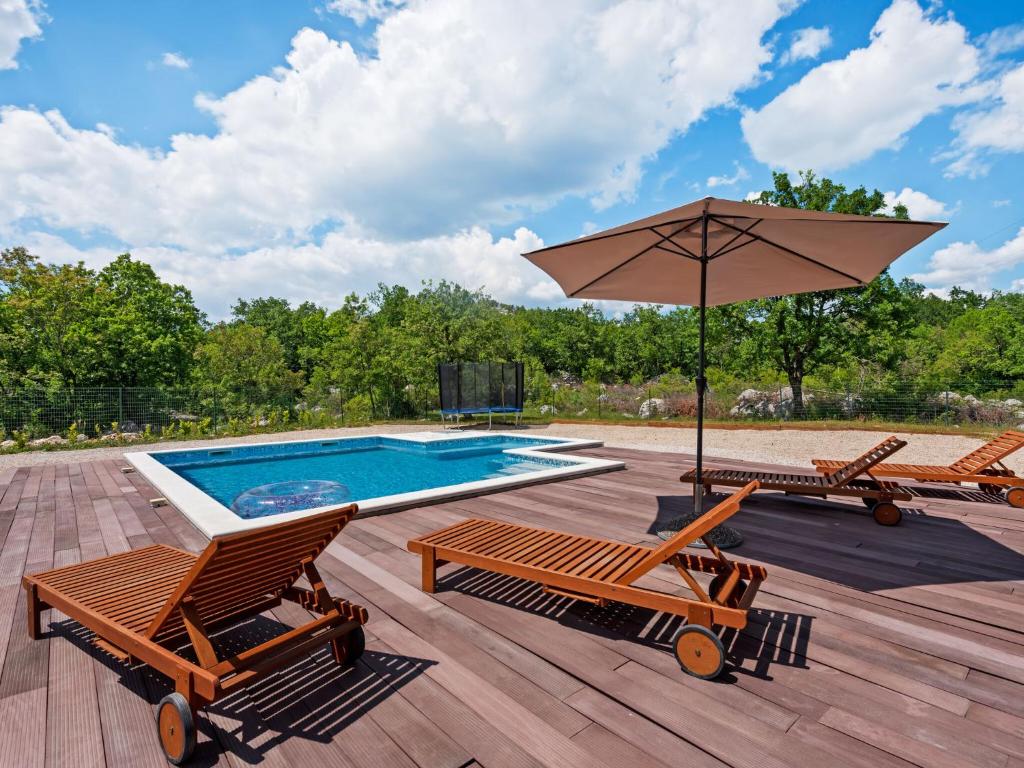 a swimming pool with two chairs and an umbrella at Bonaventura Countryside Villa near Split in Neorić
