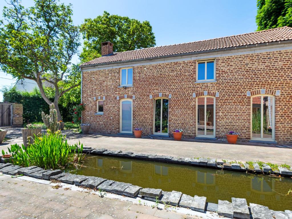 a brick house with a pond in front of it at Cozy apartment in the hiking and cycling kingdom of Geetbets in Geetbets