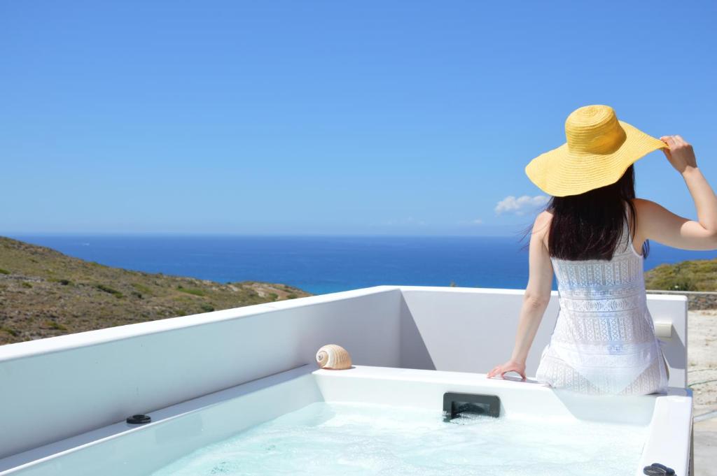 a woman in a hat sitting in a bath tub at Milos Zen Suites in Adamantas