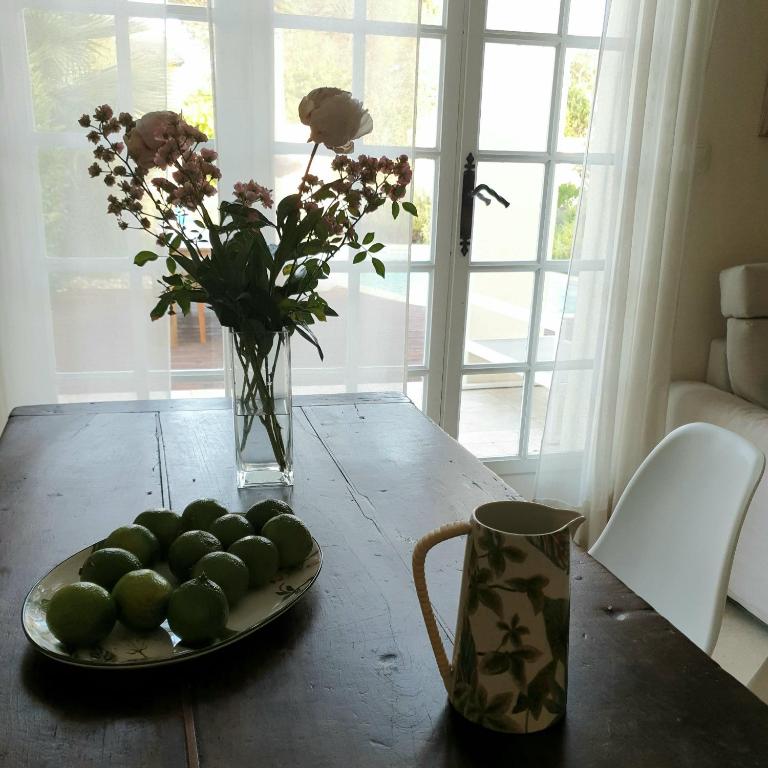 a table with a plate of limes and a vase of flowers at Bastide Philomen in Pérols