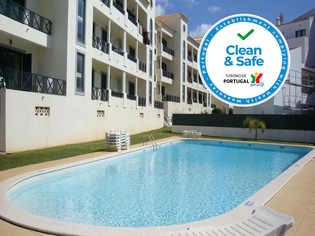a swimming pool in front of a building with the clean and safe sign at Cravinho in Albufeira