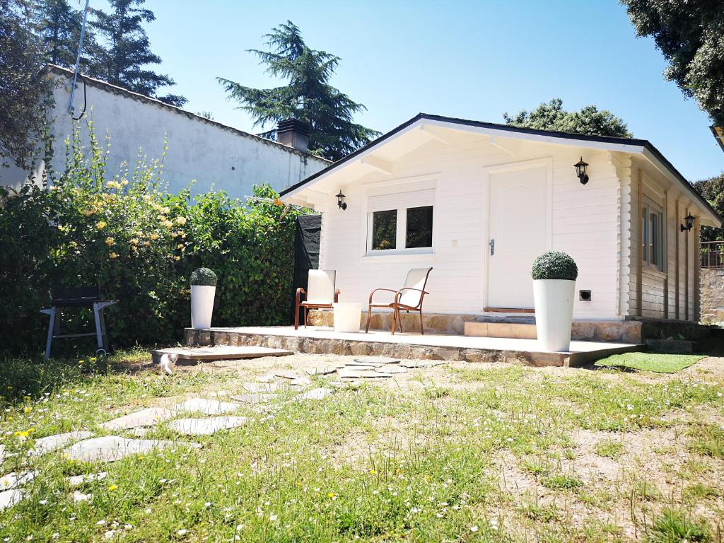 ein kleines weißes Haus mit zwei Stühlen im Hof in der Unterkunft La Casita del Escorial in El Escorial