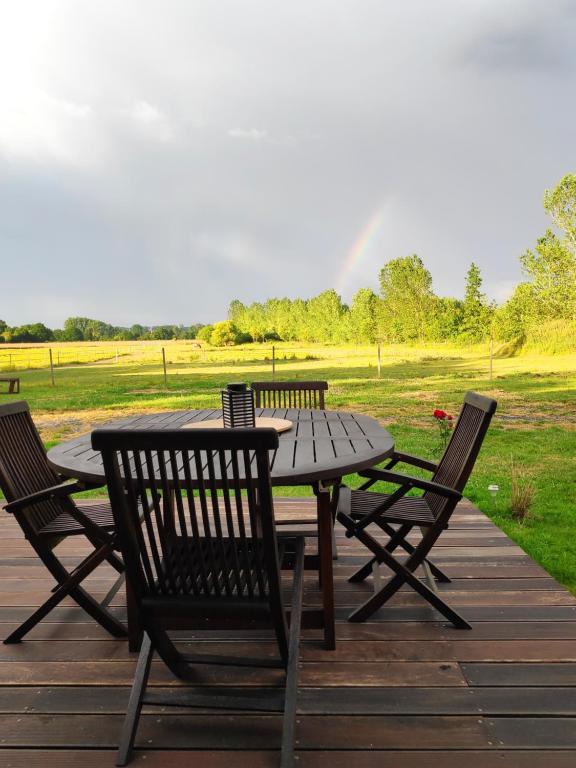 einen Holztisch und Stühle auf einer Terrasse mit einem Feld in der Unterkunft gîte du bien être in Hodeng-Hodenger
