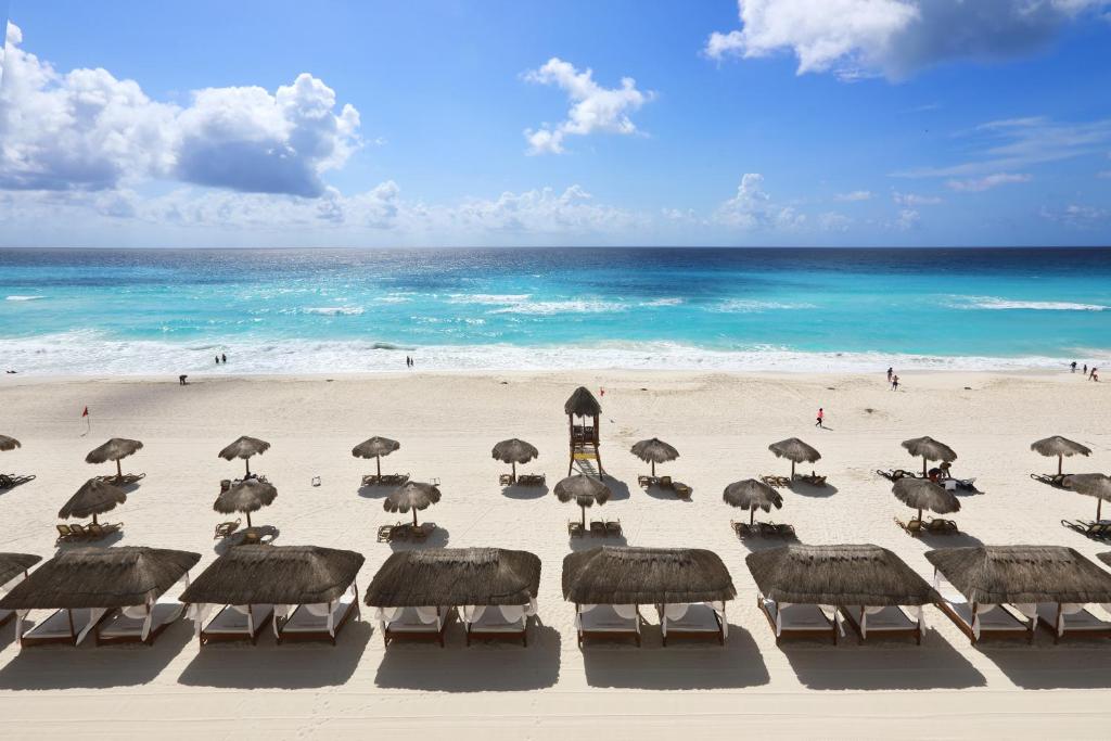 a group of umbrellas on a beach with the ocean at Emporio Cancun - Buy All Inclusive Option in Cancún
