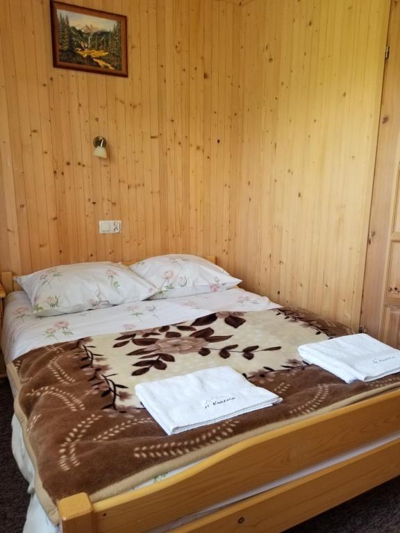 a bed in a wooden room with towels on it at Pokoje U Kantora in Bukowina Tatrzańska