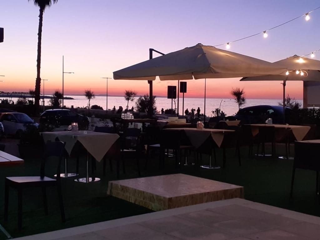 a restaurant with tables and umbrellas in front of the ocean at Bari Lory’s Home in Bari