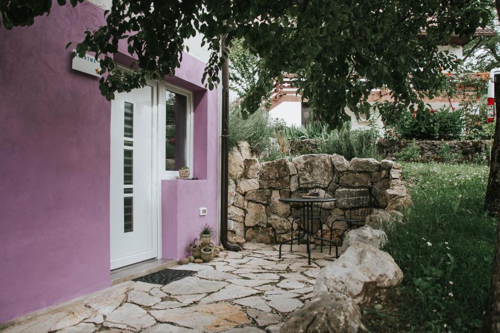une maison violette avec une table et un mur en pierre dans l'établissement Studio Pod hruško, à Kobarid
