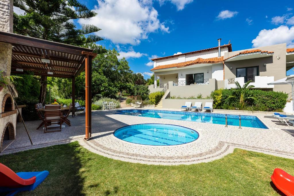 a backyard with a swimming pool and a house at Alonia Villa, magic ambience, By ThinkVilla in Melidhónion