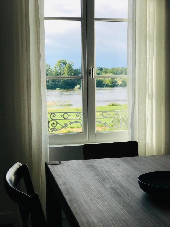 a table and a window with a view of a river at Au pied du Chateau de Chaumont sur Loire in Chaumont-sur-Loire