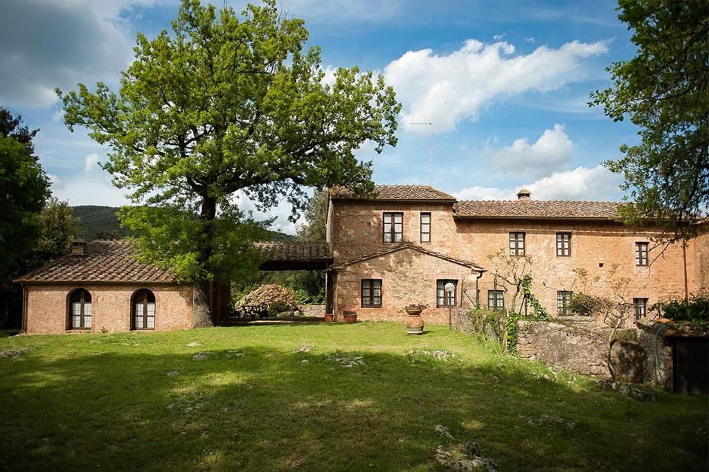 una gran casa de ladrillo con un árbol en el patio en Casa al Gianni en Sovicille