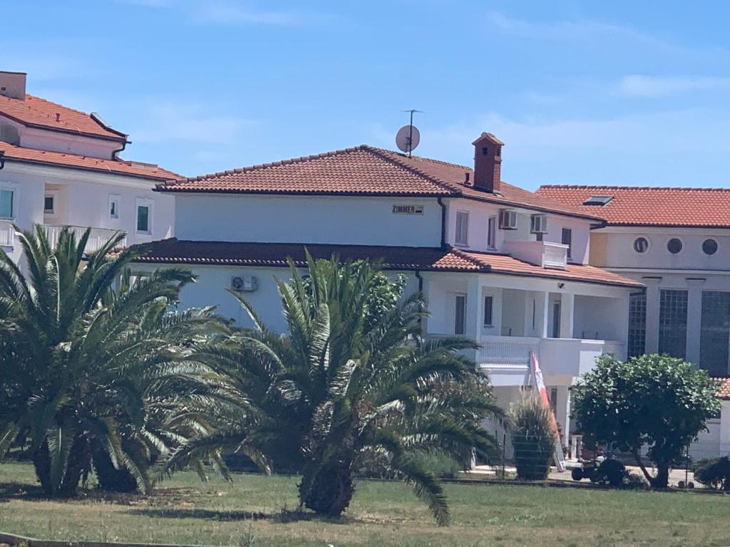 un gran edificio blanco con palmeras delante en Villa Osipovica, en Medulin