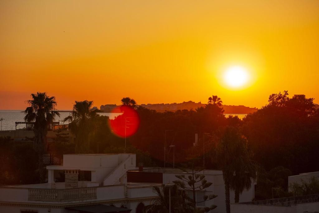 einen Sonnenuntergang über einer Stadt mit einem Gebäude und Bäumen in der Unterkunft SeaBreeze Baia Verde in Baia Verde