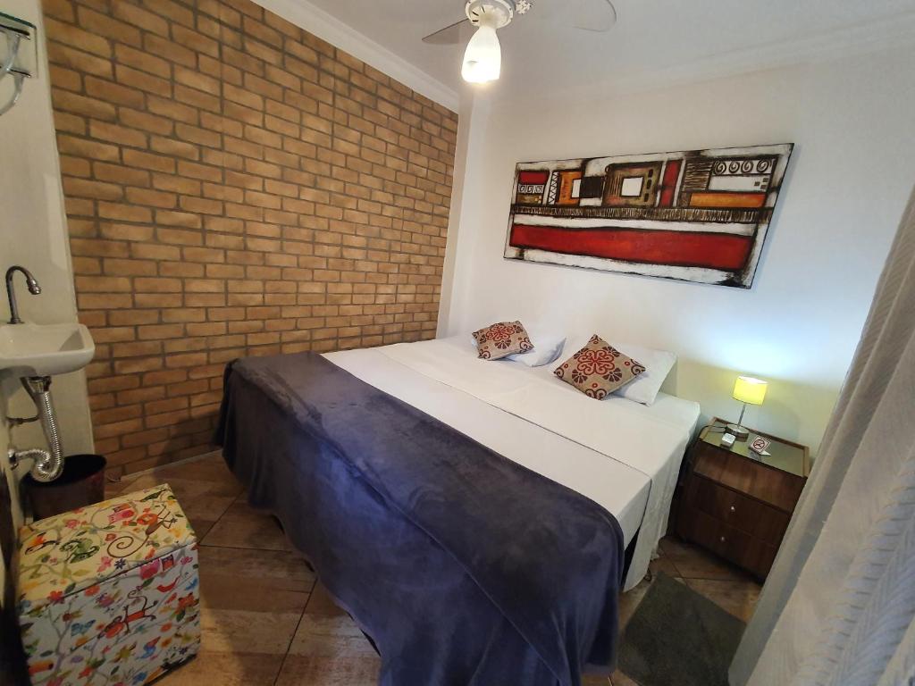 1 dormitorio con 1 cama con pared de ladrillo en HostelariaSP Boutique, en São Paulo