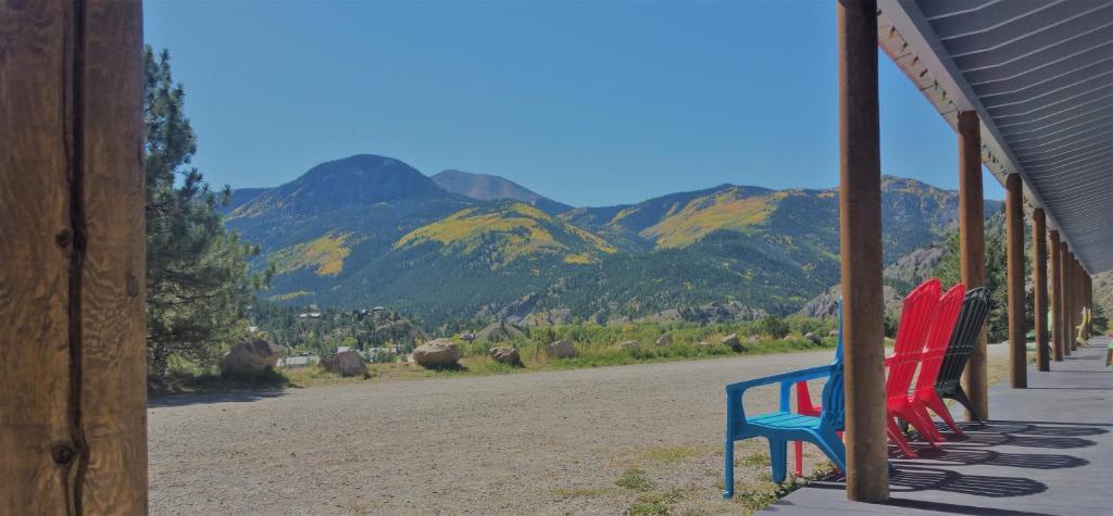 - une rangée de chaises rouges et bleues sur une terrasse couverte avec des montagnes dans l'établissement Alpine Moose Lodge, à Lake City