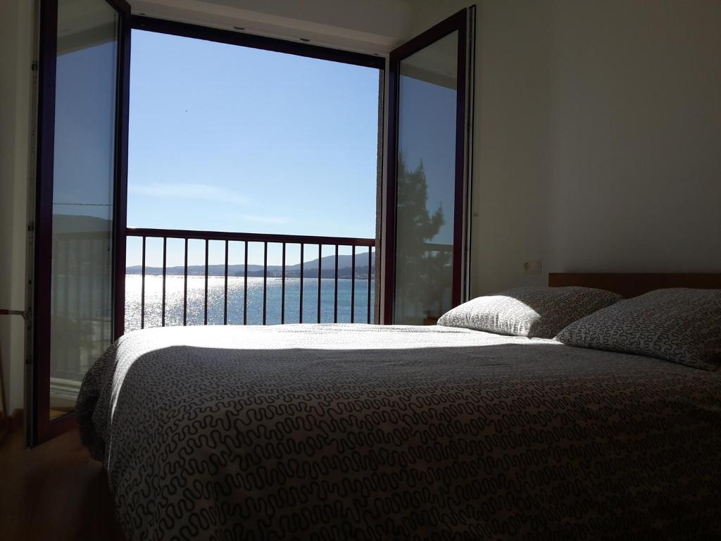 una camera con un letto e una grande finestra di Apartamento Playa de Boiro a Boiro
