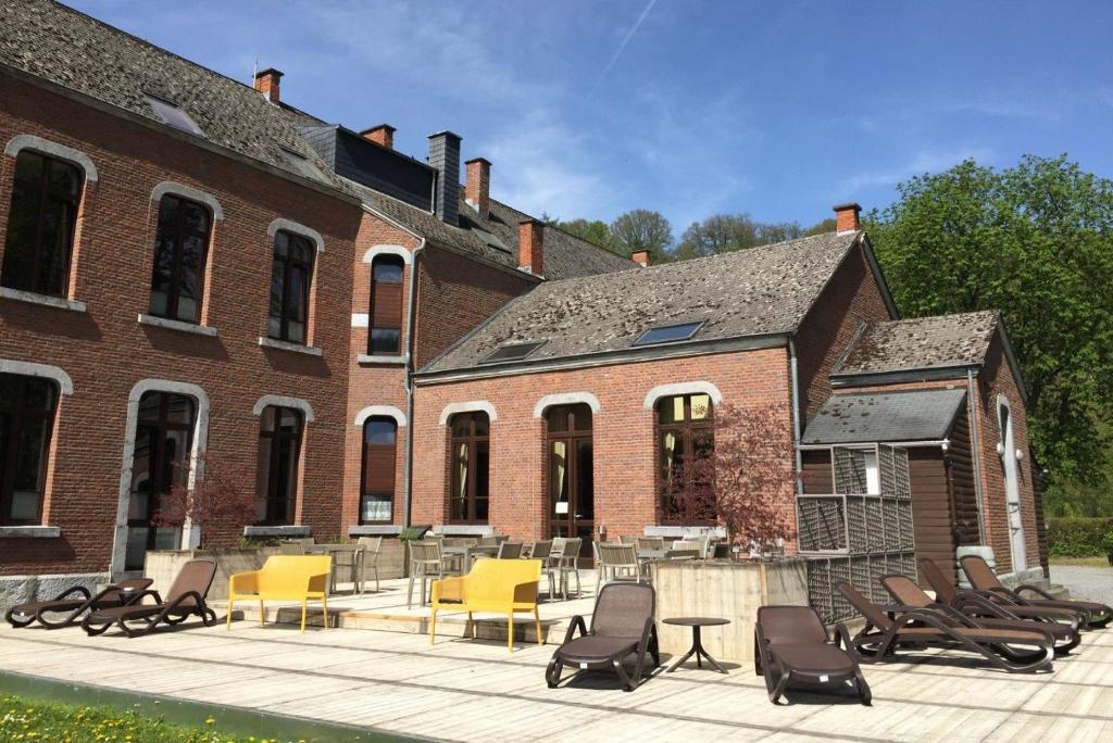 un grand bâtiment en briques avec des chaises et une table dans l'établissement Hotel des Comtes Durbuy, à Durbuy