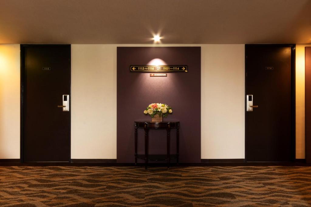 a lobby with three doors and a vase of flowers on a table at Toyo Hotel in Fukuoka