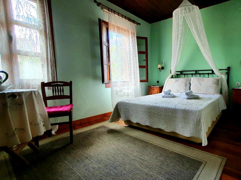 um quarto com uma cama, uma cadeira e janelas em Varosi Guesthouse em Edessa