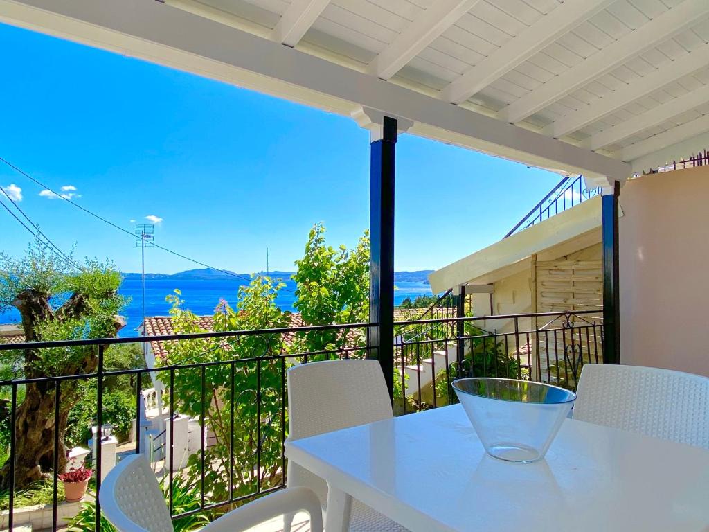 una mesa blanca y sillas en un balcón con vistas al océano en Nissaki Apartments and Vasilis House, en Nisakion