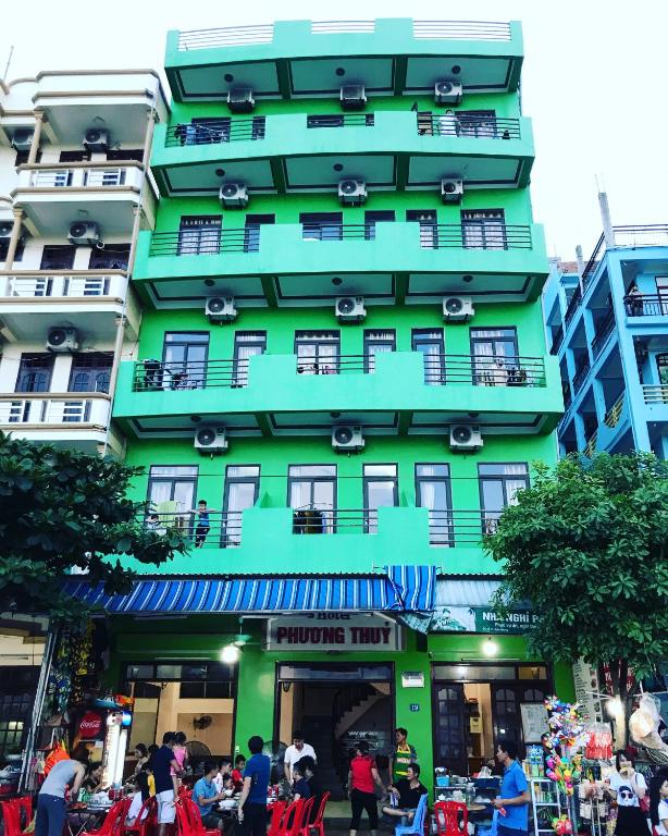 a green building with people walking in front of it at Phương Thuỷ Hotel in Sầm Sơn