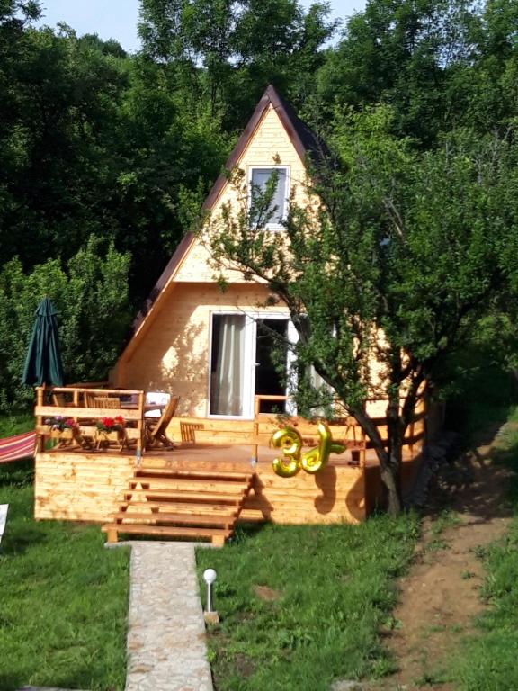 eine kleine Hütte mit einer Veranda und einem Baum in der Unterkunft Cabana din livada in Pucioasa