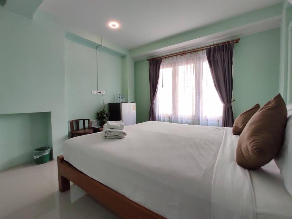 a bedroom with a large white bed with a window at Ban Mae Boonthong in Lampang