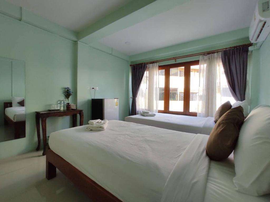a bedroom with a large white bed with a window at Ban Mae Boonthong in Lampang