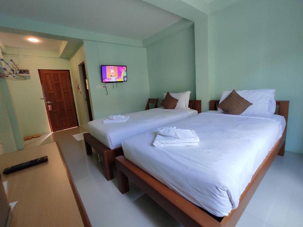 two twin beds in a room with a tv at Ban Mae Boonthong in Lampang