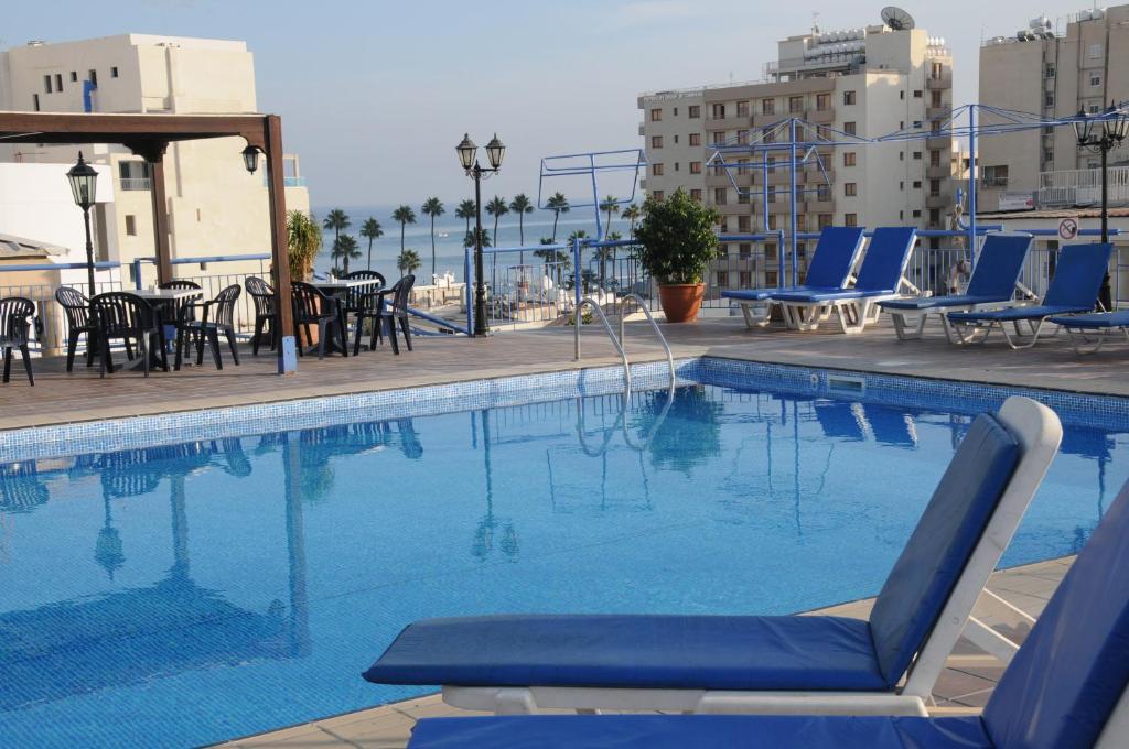 una piscina con sillas y mesas en un edificio en Atrium Zenon Hotel Apartments en Lárnaca