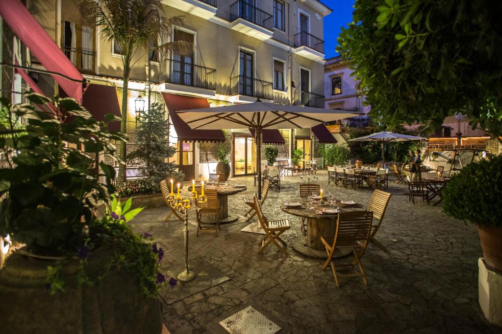 um pátio exterior com mesas e guarda-sóis à noite em Hotel Victoria Maiorino em Cava deʼ Tirreni