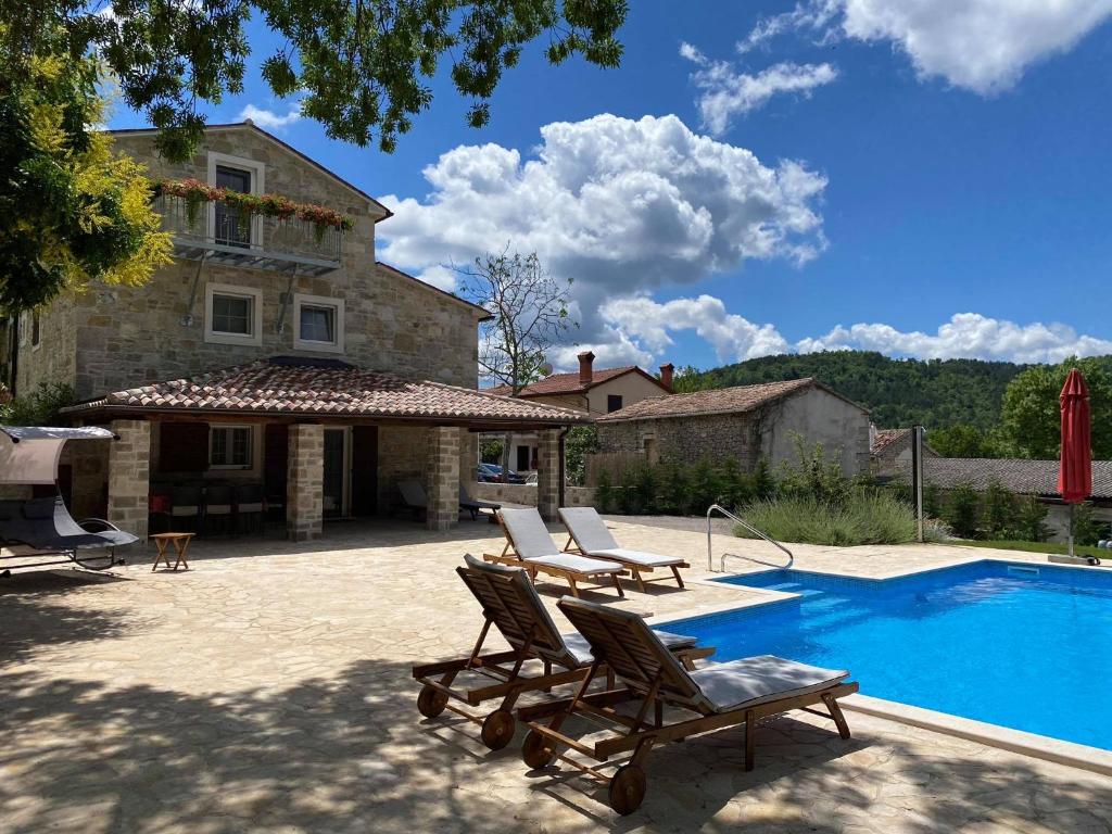 a villa with a swimming pool and two lounge chairs at Casa di nonno Giovanni in Buzet