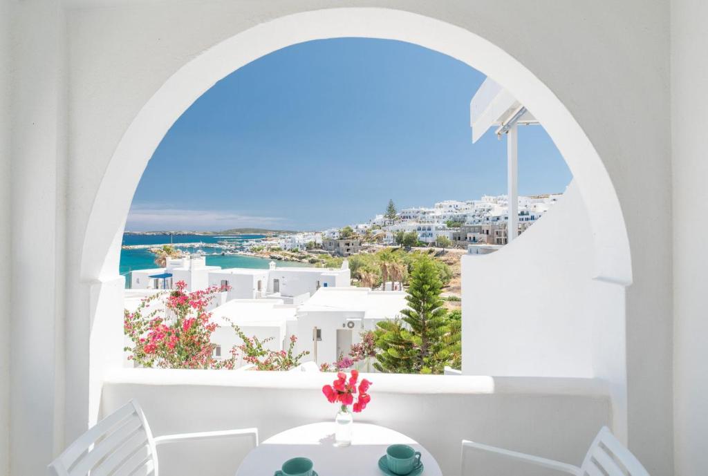 a white dining room with a view of the ocean at Adonis Hotel Studios & Apartments in Naousa