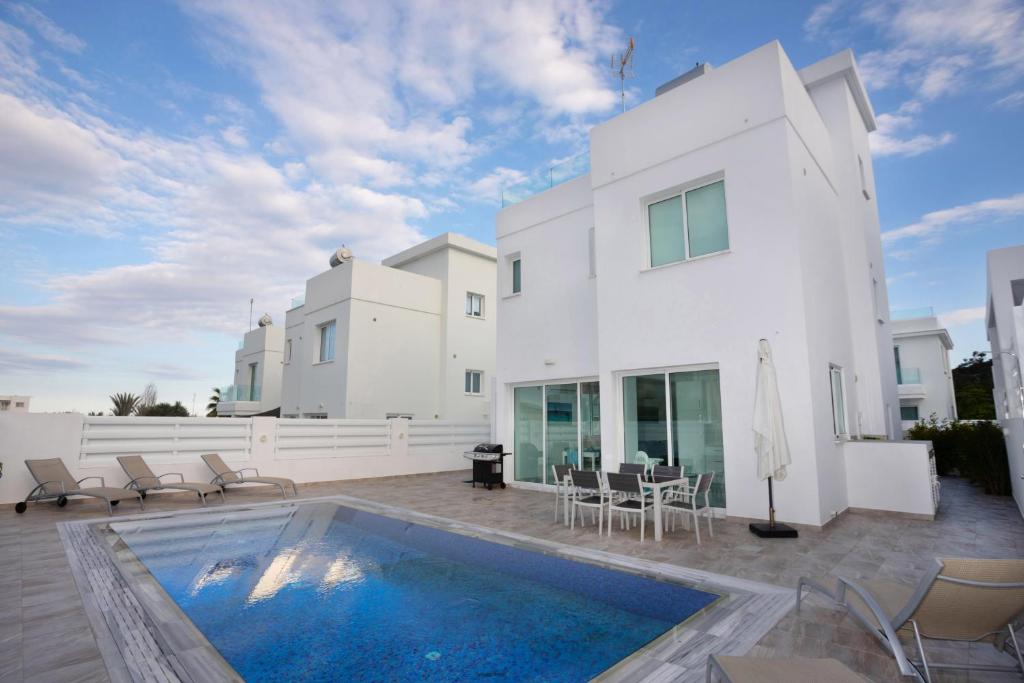 une maison blanche avec une piscine en face de celle-ci dans l'établissement Villa Ioli Green Bay by TrulyCyprus, à Protaras