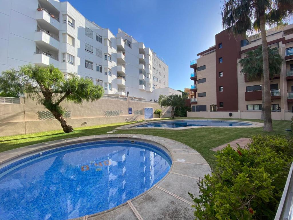 APARTAMENTO 2ª LINEA DE PLAYA في روكويتاس دي مار: مسبح في شقة فيها مباني في الخلف