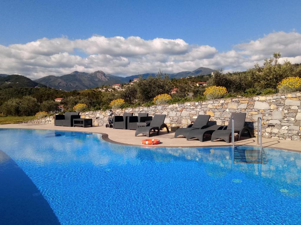 a swimming pool with chairs and a rock wall at Appartamento Leccino con piscina - Riva Trigoso in Sestri Levante