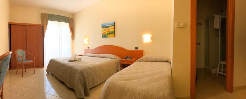 a hotel room with two beds and a window at Hotel Mille Pini in Ginosa Marina