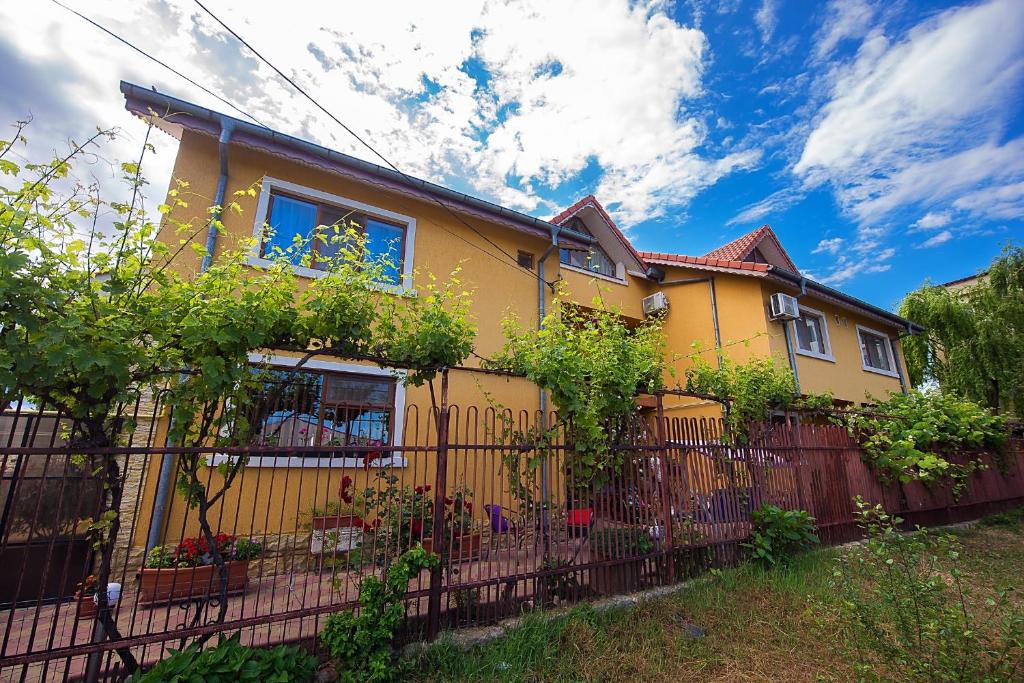a yellow house with a fence in front of it at Vila Levent Mangalia in Mangalia