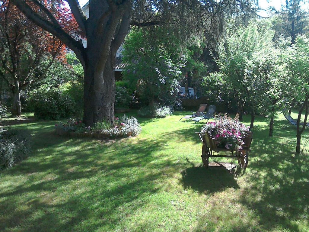 un banc avec des fleurs dans l'herbe dans l'établissement Le Jardin Sarlat, à Sarlat-la-Canéda