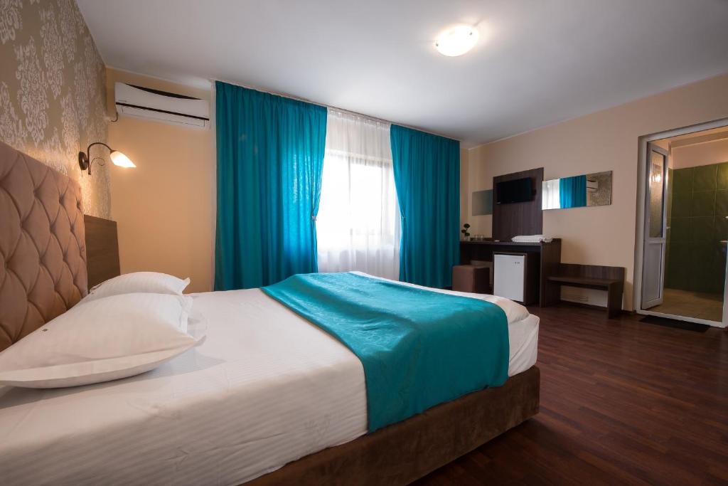 a bedroom with a large bed with blue curtains at Vila Levent Mangalia in Mangalia