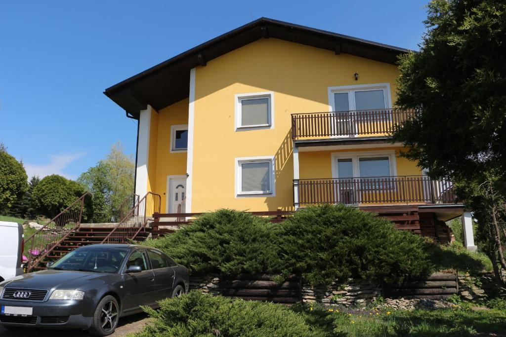 ein gelbes Haus mit einem davor geparkt in der Unterkunft Apartmány NIVA in Široká Niva