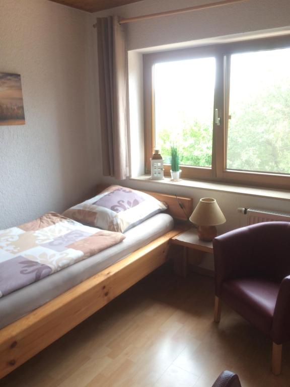 a bed in a room with a window and a chair at Ferienwohnung Saaletalblick in Jena