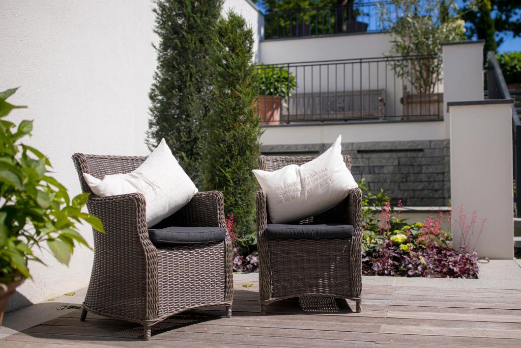 two wicker chairs with pillows sitting on a patio at Strandhotel Fontana in Timmendorfer Strand