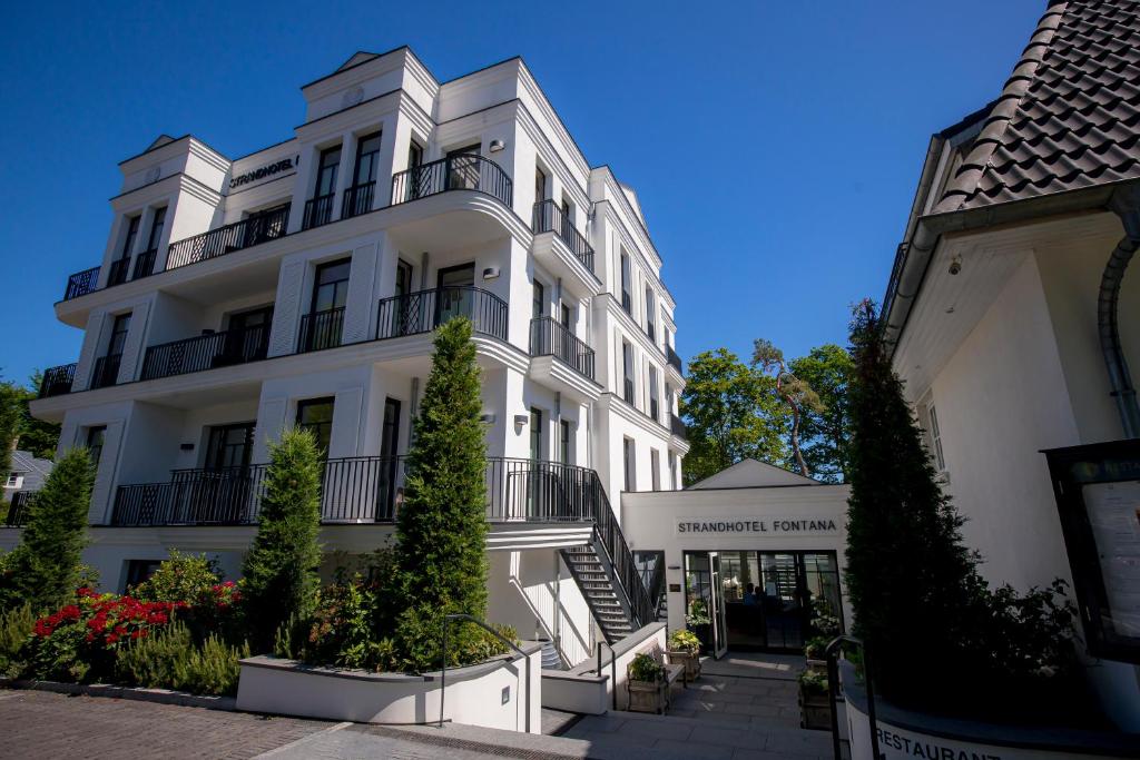 a white building with plants in front of it at Strandhotel Fontana in Timmendorfer Strand