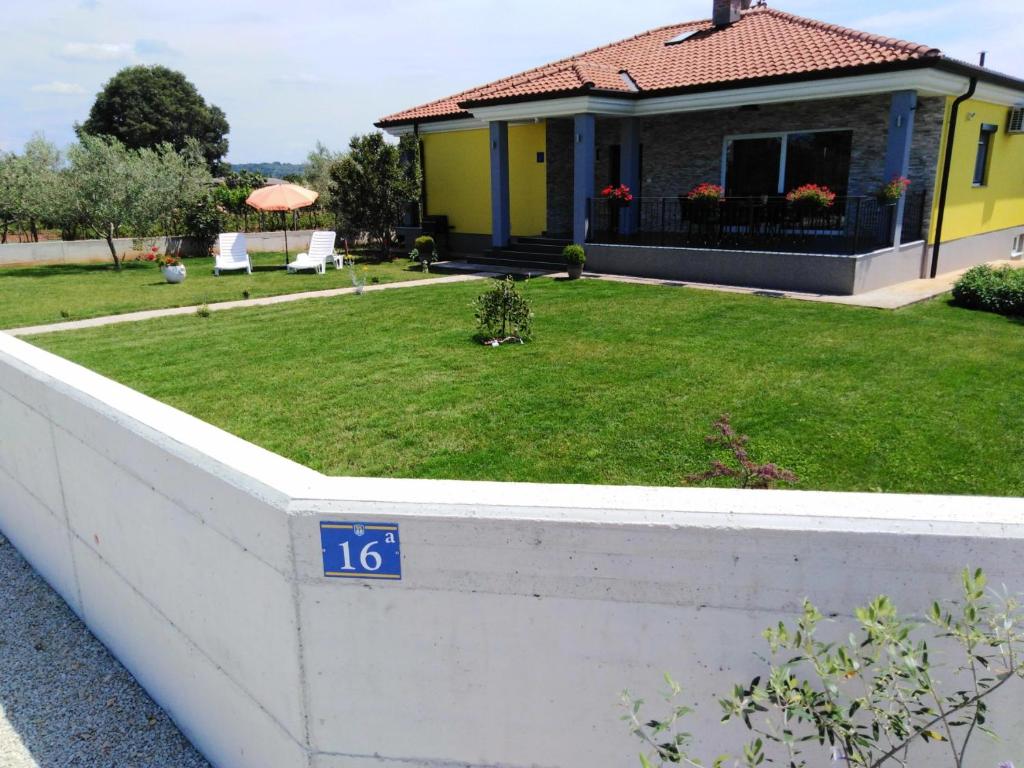 a house with a retaining wall with a yard at Holiday house ANITA in Umag