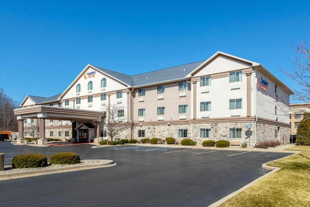 a large white building with a parking lot at Comfort Suites Stevensville – St. Joseph in Stevensville