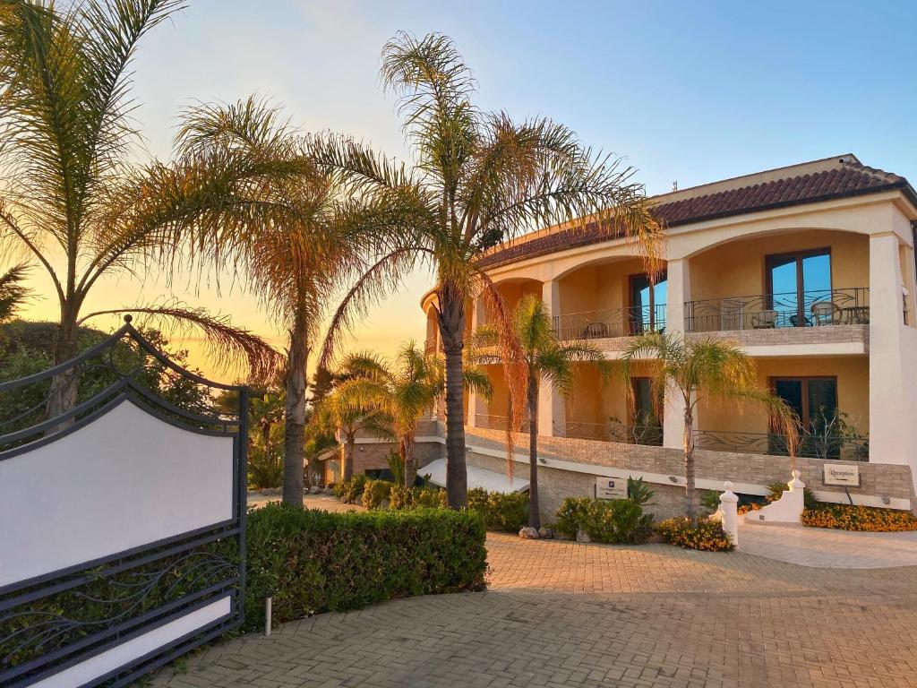 un grand bâtiment avec des palmiers devant lui dans l'établissement Blu Tropical Resort, à Zambrone